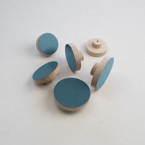 Könnte beinhalten: Sechs runde Holzgriffe mit einer tealblauen lackierten Oberseite. Die Griffe haben ein kleines Loch in der Mitte zum Befestigen.