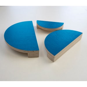 Könnte beinhalten: Drei halbkreisförmige Holzformen, die in einem leuchtenden Türkisblau lackiert sind. Die Formen sind unterschiedlich groß und übereinander gestapelt.
