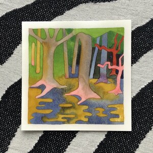 May include: Watercolor painting of a forest scene with stylized trees. The trees have pink and brown trunks, with green and blue foliage. The ground is a mix of yellow and blue, suggesting water or reflections. The artwork is on a white square.