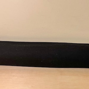 May include: A black door sweep with a soft, textured surface. The sweep is installed at the bottom of a white door.