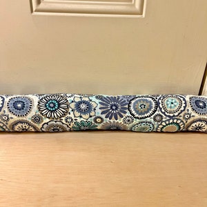 May include: A blue and white floral patterned doorstop. The doorstop is a cylinder shape and is made of fabric.