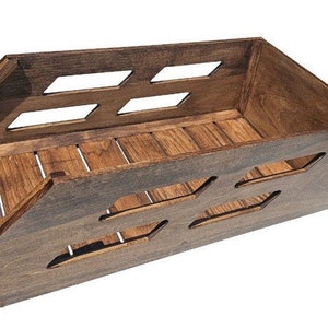 May include: A dark brown wooden crate with a rectangular shape and open sides. The crate has a series of rectangular cutouts on the front and sides, and a slatted bottom.
