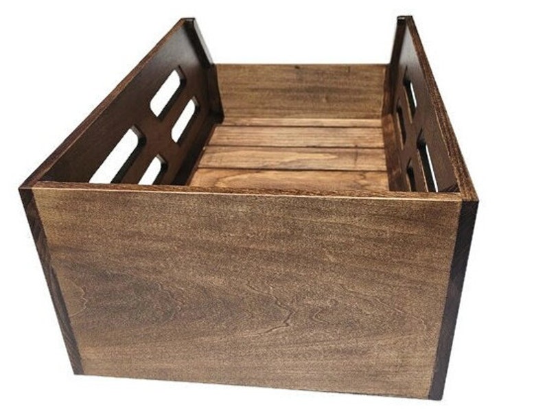 May include: A dark brown wooden storage crate with a slatted design on the front and sides. The crate is made of solid wood and has a natural finish.
