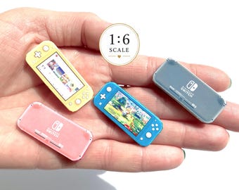 May include: Four miniature 1:6 scale Nintendo Switch game consoles in yellow, blue, pink, and grey. The yellow and blue units display active game screens, while the pink and grey units show the back with the Nintendo Switch logo and text.