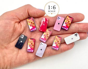 Può includere: Una collezione di repliche di smartphone in miniatura in scala 1:6 in vari colori, tra cui nero, bianco, rosa e rosso. Ogni piccolo dispositivo presenta uno schermo con icone di app o un retro solido con obiettivo della fotocamera e logo.