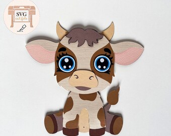 May include: A brown and white paper cut-out of a cartoon cow with big blue eyes. The cow is sitting with its legs crossed and has a brown tail.