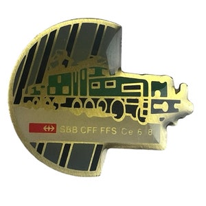 May include: A gold-colored metal pin with a green and black locomotive design. The pin features the text "SBB CFF FFS Ce 6/8" and a Swiss flag.