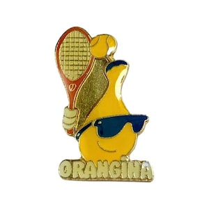 May include: A yellow cartoon character wearing sunglasses and holding a red and white tennis racket. The character is holding a yellow tennis ball. The character is standing on a gold banner with the word "Orangina" written in white letters.