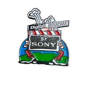 Könnte beinhalten: Eine Comicfigur hält eine Filmklappe mit dem Text "Digital Betacam by Sony". Die Figur trägt eine rote Hose und weiße Schuhe. Die Filmklappe ist rot und weiß mit schwarzem Hintergrund.