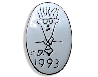 May include: White oval pin with a black and white cartoon drawing of a person wearing glasses and a tie. The text "F.D. 1993" is below the drawing.