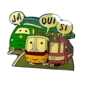 Puede incluir: Un pin de tren de dibujos animados verde, amarillo y rosa con tres vagones. El primer vagón tiene un globo de diálogo que dice "JA", el segundo vagón tiene un globo de diálogo que dice "OUI", y el tercer vagón tiene un globo de diálogo que dice "SI".