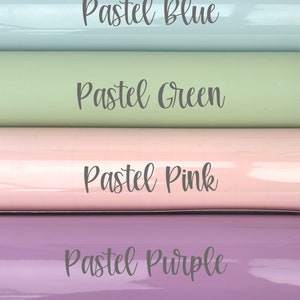 May include: Four rolls of pastel-colored vinyl are displayed, each labeled with a different color: Pastel Blue, Pastel Green, Pastel Pink, and Pastel Purple. The rolls are arranged horizontally, showcasing their glossy finish and soft hues.