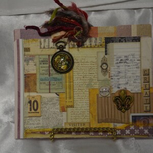 May include: A vintage-style scrapbook featuring a range of paper textures and embellishments, including a pocket watch, a fleur-de-lis charm, and the word "CREATE" spelled out in letter tiles. The scrapbook also includes the words "VISITER" and "LONDON".