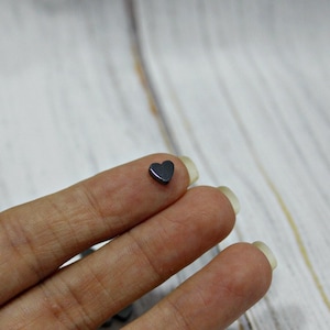 May include: A small, black heart-shaped charm made of hematite.