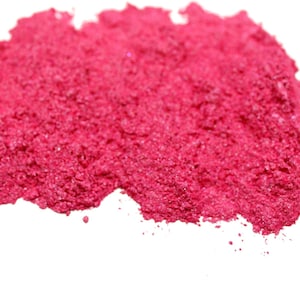 May include: A close-up of a pile of bright pink mica powder. The powder is fine and shimmery, with a slightly iridescent sheen.