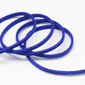 May include: Close-up of a blue suede cord, showing the texture and color of the material. The cord is coiled in a loose circle.