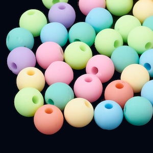 May include: A collection of pastel colored round beads. The beads are made of a smooth, matte material and are arranged in a random pattern.