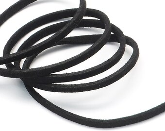 May include: Close-up of a coiled black cord, likely suede or leather, against a white background. The cord is round and appears to be soft and flexible, with a slightly textured surface. The image highlights the cord's dark color and smooth curves.