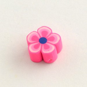 May include: A pink flower-shaped eraser with five petals. Each petal has layers of pink and white, with a blue center. The eraser is a small, colorful stationery item.