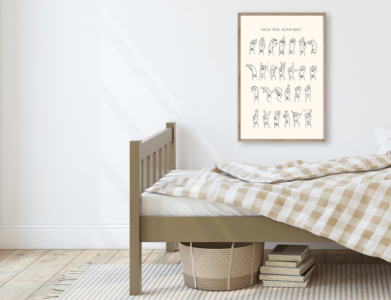 May include: A black and white illustration of the American Sign Language alphabet on a beige background. The illustration is framed and hanging on a white wall above a brown wooden bed with a beige and white checkered bedspread.