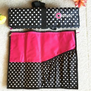 Può includere: Un rotolo per pennelli da trucco a pois neri e bianchi con fodera rosa e il testo "Creative Options" sul lembo superiore.