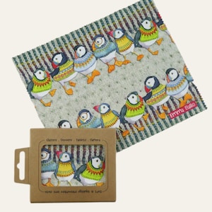 May include: A microfiber lens cloth featuring a repeating pattern of cartoon puffins in various outfits. The cloth is light green with a striped design. A cardboard box with a cutout shows the cloth and text that reads "Classes, Screens, Tablets, Camera".