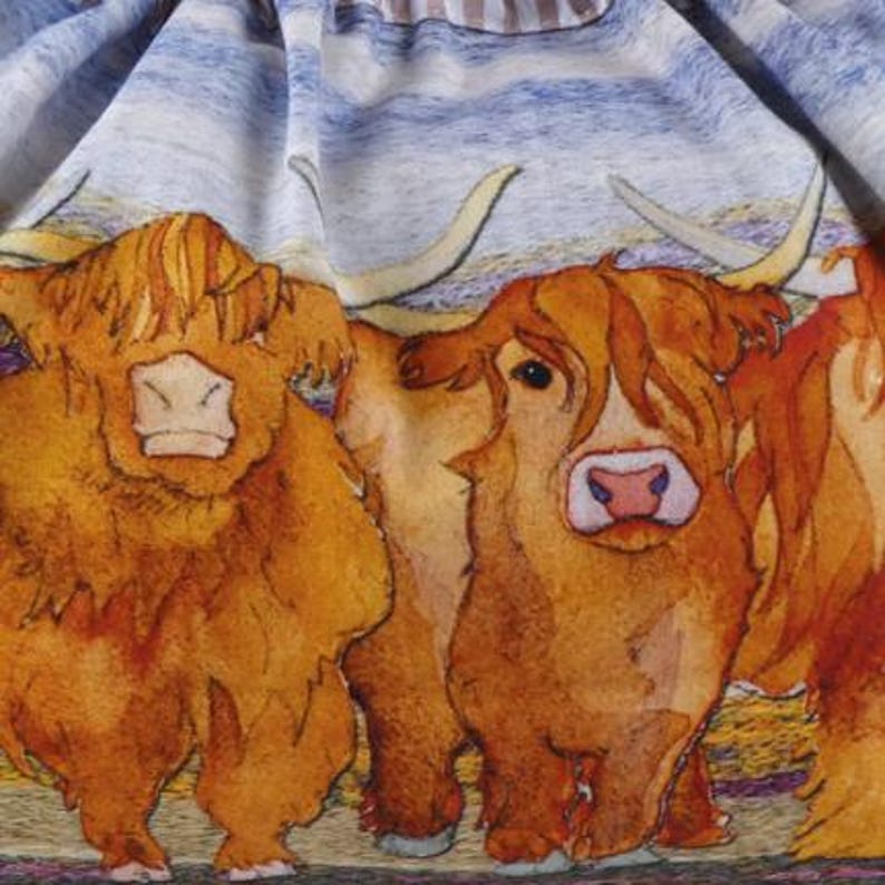 Op de afbeelding: Een stof met een herhalend patroon van ruige, gemberkleurige Schotse Hooglanders met lange, gebogen hoorns. De koeien zijn afgebeeld met gedetailleerde vachtstructuren tegen een achtergrond van horizontale blauwe en witte strepen.