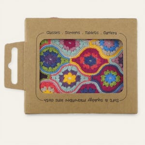 May include: A colorful crochet lens cloth in a cardboard package. The cloth features a floral pattern in shades of pink, blue, yellow, and purple. The package reads "Glasses. Screens. Tablets. Camera" and "Soft & squidgy microfibre lens cloth."