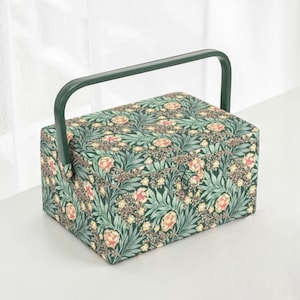 May include: A rectangular sewing box with a green handle and a floral pattern. The box is covered in a dark green fabric with a repeating pattern of pink and yellow flowers and green leaves.