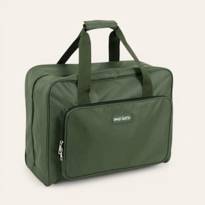 May include: An olive green sewing machine carrying case with a zippered front pocket and top handles. The bag has a rectangular shape and the text "Happy Gals" is visible on the front pocket.