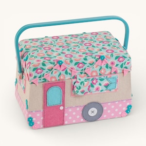 May include: A decorative sewing box shaped like a camper. The box features a floral patterned lid and accents, a pink door, and a blue handle. The body is beige with pink polka dots and felt details. A gray wheel with an X is on the side.
