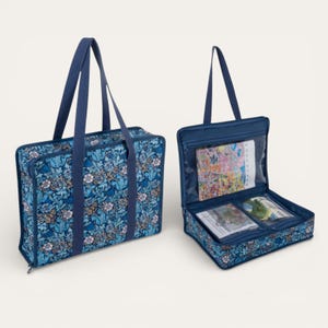 May include: Two rectangular storage bags featuring a blue floral pattern with dark blue fabric handles. One bag is closed, while the other is open, revealing clear plastic interior pockets containing various craft supplies and printed paper materials.