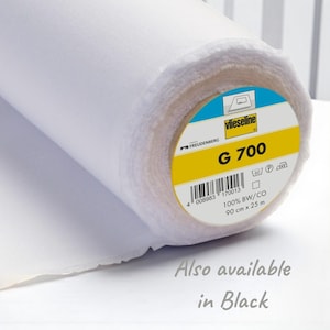 May include: A roll of white fabric with a label that reads "Vlieseline G 700". The label also indicates the fabric is 100% BW/CO and measures 90 cm x 25 m. The text "Also available in Black" is also visible.