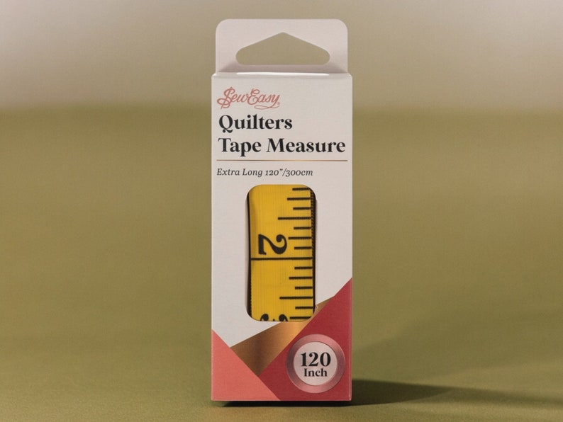 Pu&ograve; includere: Un metro a nastro Sew Easy Quilters giallo con un'etichetta bianca che dice "Extra Long 120"/300cm. Il metro a nastro &egrave; confezionato in una scatola bianca con un design rosa e oro. La scatola dice anche "Sew Easy Quilters Tape Measure" e "120 inch".