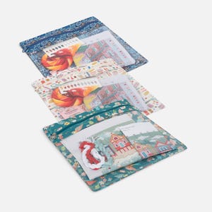 May include: Three rectangular zipped pouches with floral and bird patterns, each containing cross-stitch supplies including fabric, printed pattern charts, and bundles of colourful embroidery thread in shades of red, orange, yellow, and green.