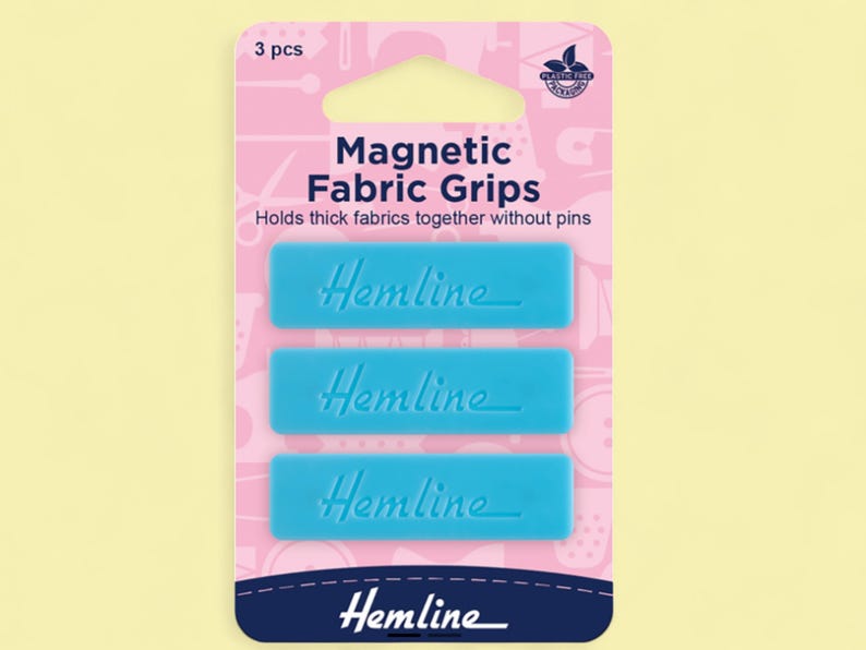 Pu&ograve; includere: Una confezione di tre pinze magnetiche blu per tessuti. La confezione rosa e bianca presenta le parole "Magnetic Fabric Grips" e "Hemline". Le pinze rettangolari sono progettate per tenere insieme tessuti spessi senza spilli.