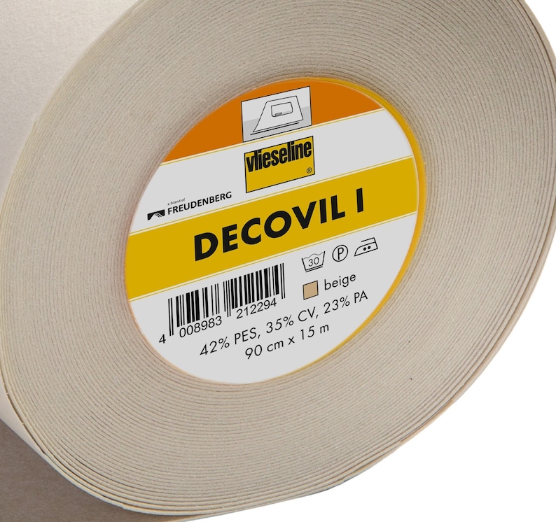 May include: A roll of beige Decovil I interfacing for sewing projects. The label reads "Decovil I" with the brand name "Vlieseline" and a product code of "008983 212294". The label also indicates the fabric composition: 42% PES, 35% CV, 23% PA. The roll is 90 cm x 15 m.