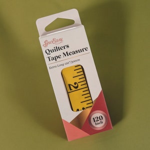 Pu&ograve; includere: Un metro a nastro Sew Easy Quilters giallo in una scatola bianca con un accento rosa e oro. Il metro a nastro &egrave; extra lungo, 120 pollici o 300 cm.