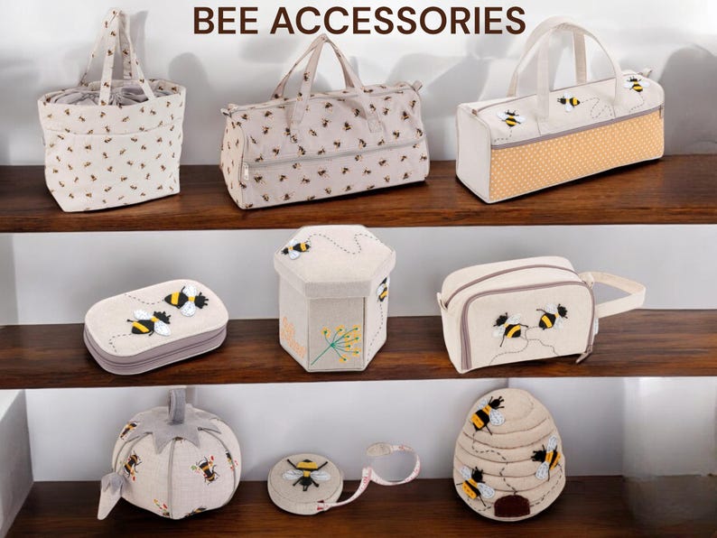 May include: A collection of bee-themed accessories, including tote bags, a travel bag, a cosmetic bag, a sewing kit, a hexagonal storage box, a pincushion, and a tape measure. The items are beige with black and yellow bee designs. The text "BEE ACCESSORIES" is at the top.