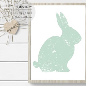 Puede incluir: Una impresi&oacute;n de arte imprimible con una silueta verde claro de un conejo con una textura desgastada. La impresi&oacute;n est&aacute; enmarcada en un marco de madera claro y tiene el texto "High Quality Printable Up to 24x36 inches" en la parte superior.