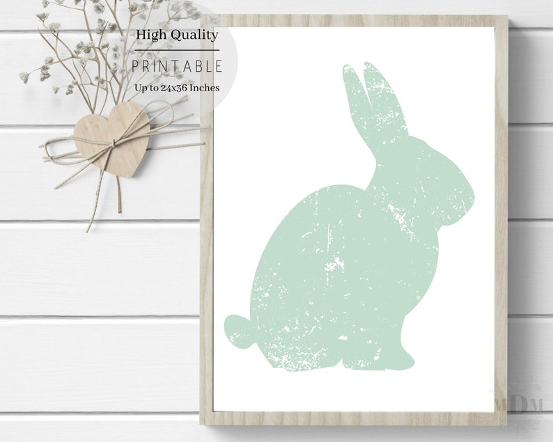 Puede incluir: Una impresi&oacute;n de arte imprimible con una silueta verde claro de un conejo con una textura desgastada. La impresi&oacute;n est&aacute; enmarcada en un marco de madera claro y tiene el texto "High Quality Printable Up to 24x36 inches" en la parte superior.