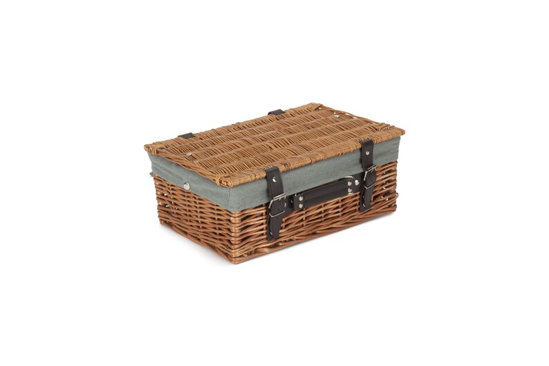 May include: A woven wicker picnic basket with a light blue canvas lid and brown leather straps and buckles.