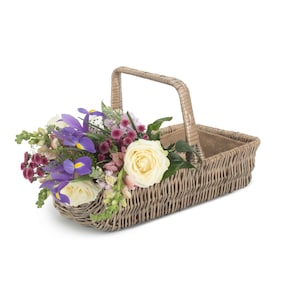 May include: A wicker basket with a handle, filled with a bouquet of purple irises, white roses, and pink flowers.
