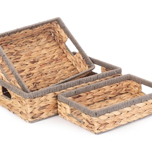 May include: Three woven baskets with grey trim. The baskets are made of natural materials and are stacked on top of each other.