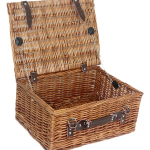 May include: A brown wicker picnic basket with a leather handle and metal clasps. The lid is open and the basket is empty.