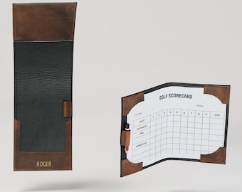 May include: A brown leather golf scorecard holder with a black interior and the word "ROGER" embossed in gold. The holder is open to reveal a white scorecard with the words "GOLF SCORECARD" printed at the top.