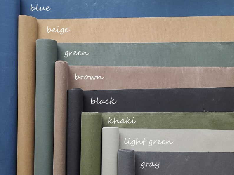 K&ouml;nnte beinhalten: Eine Sammlung von Stoffrollen in verschiedenen Farben, darunter Blau, Beige, Gr&uuml;n, Braun, Schwarz, Khaki, Hellgr&uuml;n und Grau. Die Stoffrollen sind in einem vertikalen Stapel angeordnet, wobei die blaue Rolle oben und die graue Rolle unten liegt.