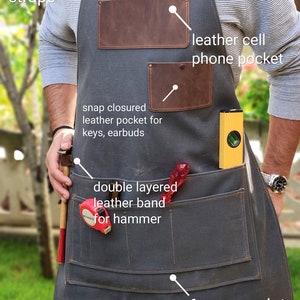May include: A gray canvas work apron with adjustable leather straps, multiple pockets, and a leather phone pocket. The apron is made of 20 oz. waxed canvas and has a double-layered leather band for a hammer.
