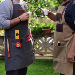 May include: Two people wearing canvas and leather work aprons with multiple pockets. The aprons have various tools in the pockets, including a level, a hammer, and a tape measure.