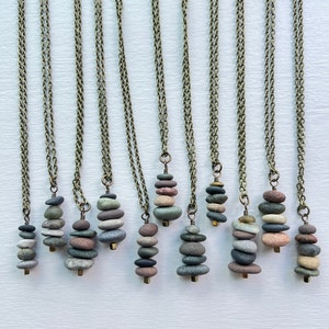 May include: A collection of 12 necklaces featuring stacked stone pendants. Each pendant is made of different colored stones, creating a unique and natural look. The necklaces are made with a brass chain.